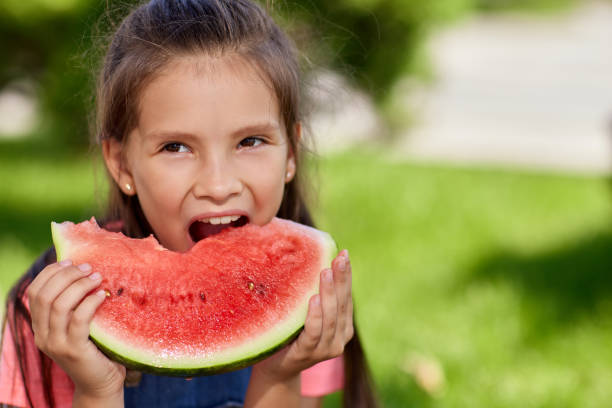 istock child girl eats a watermelon in sunny day 1339621793