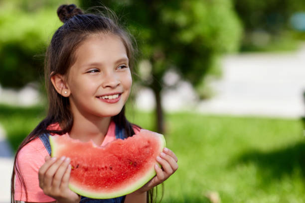 istock child girl eats a watermelon in sunny day 1339621832