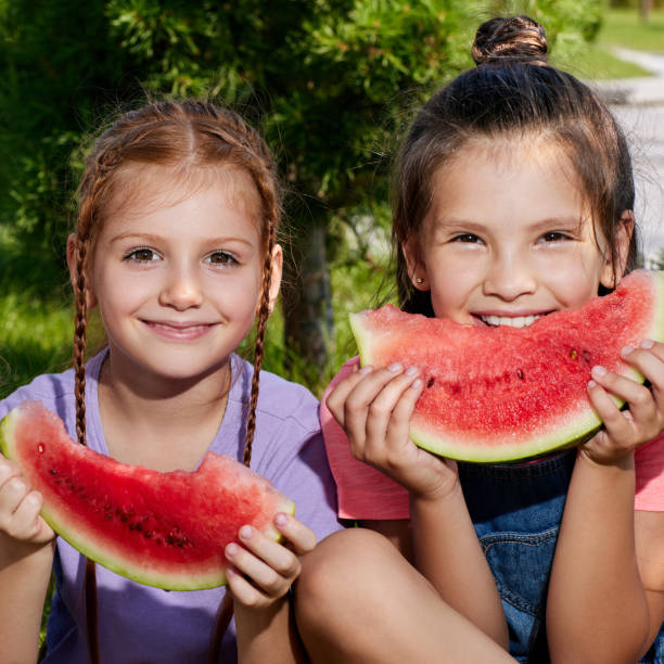 istock child girl eats a watermelon in sunny day 1339621879