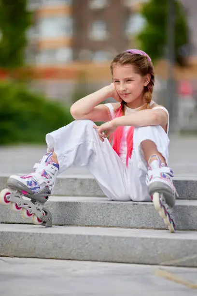 Photo of cute little girl on roller skates at park.
