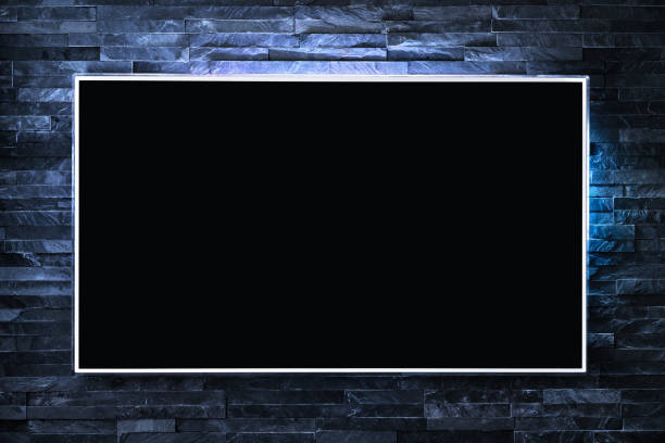 Tv screen on wall at night in dark with led light. Television and flat smart monitor display on blue brick background. Modern futuristic loft living room or lounge. stock photo