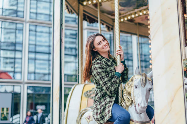 frau auf karussellfahrt mit spaß - carousel horses stock-fotos und bilder