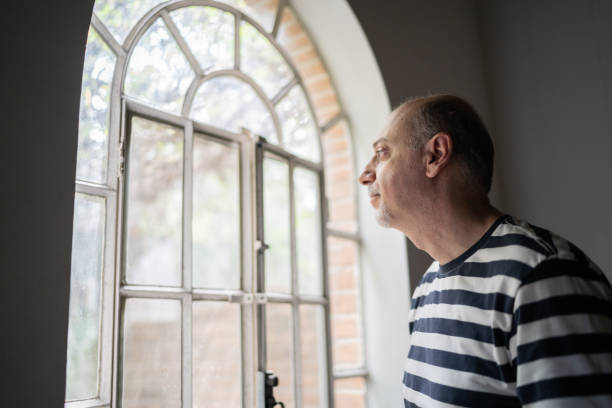 istock Man looking through the window at home 1339629747