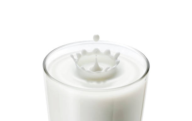 Gros plan de la goutte de lait dans le verre créer une vague ondulée et des éclaboussures en forme de couronne montrent lait frais, aliments sains, concept de boisson pour le petit-déjeuner. Laisser tomber du lait dans du verre à lait fait des vagues  - Photo