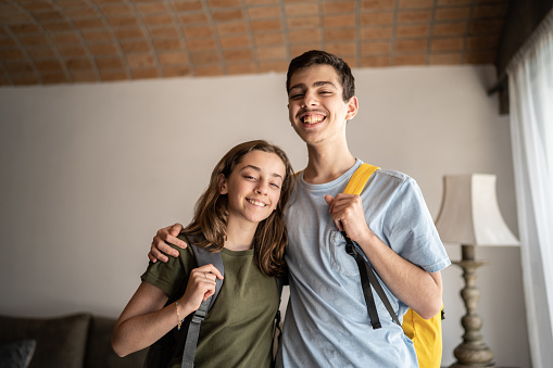 Portrait of a teenager siblings with backpack at home