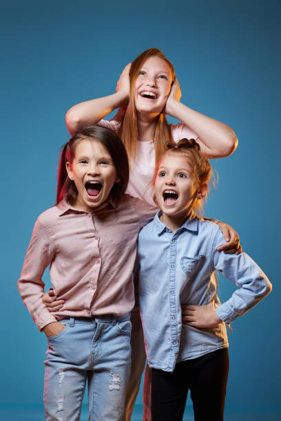 istock three kids girls standing together on blue background 1339631771