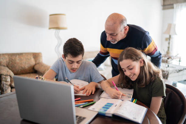 istock Father helping son and daughter with homework at home 1339635002