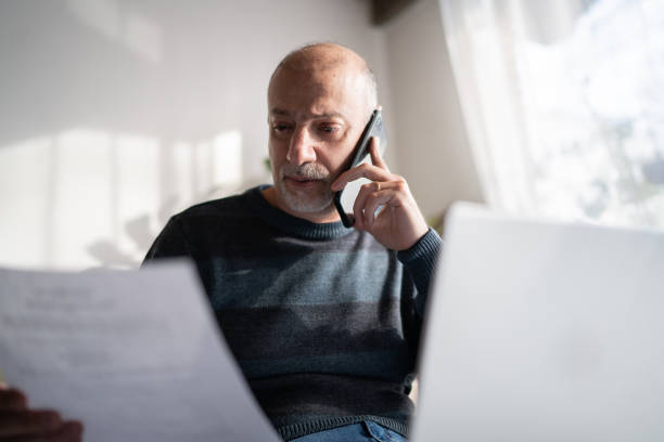 istock Mature man talking on the phone and using laptop at home 1339635404