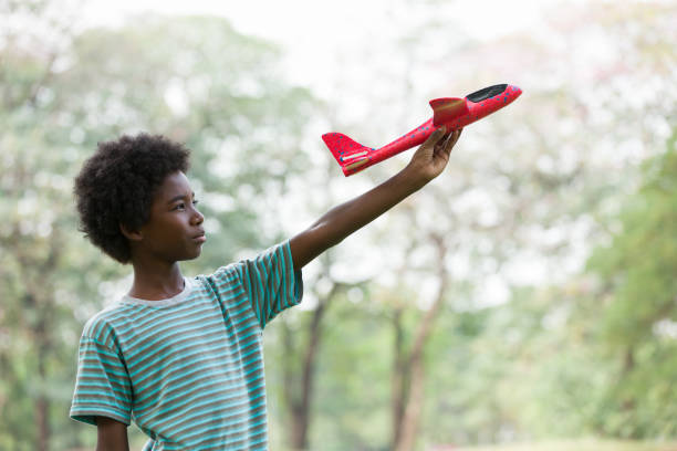 afroamerikanischer junge, der mit spielzeugflugzeug im freien spielt. kind, das spaß mit dem spielzeugflugzeug im park hat. glückliche schwarze. bildungs- und exkursionenkonzept - pre teen boy stock-fotos und bilder