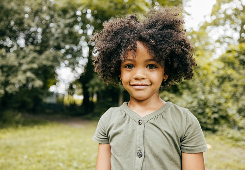 Portrait of cute African-American girl smiling and looking at the camera while she is at the park.