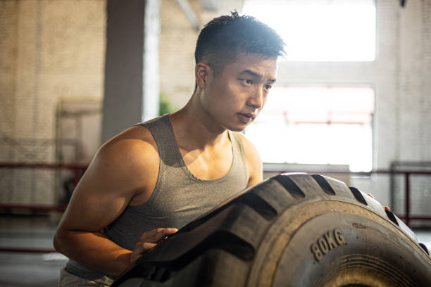 African American man (20s) doing strength training exercises using tractor tire.