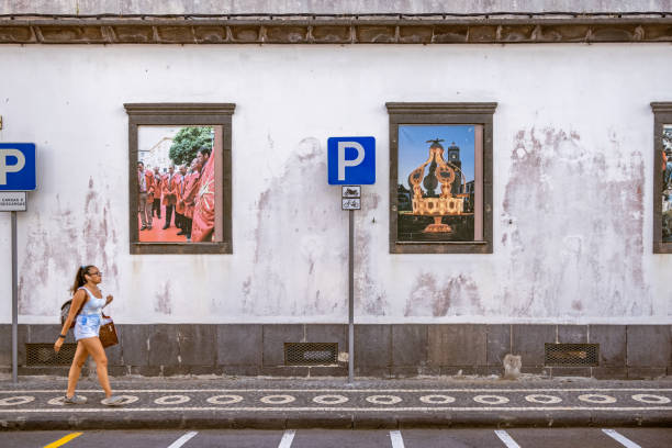 One young woman passing a wall with advertisement posters in a street in the Azorean city Ponta Delgada
