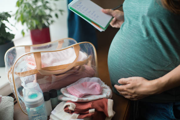 Pregnant woman preparing bag for the hospital for childbirth Pregnant woman at home preparing bag for newborn baby childbirth stock pictures, royalty-free photos & images