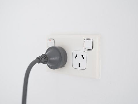 Unrecognizable woman plugging in an electricity plug into the plug socket hub close up. Woman insert a device charging USB adapter into plug socket hub.