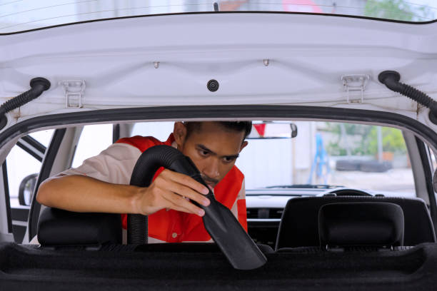 Details of car vacuum cleaning. Professional cropped male worker using wet vacuum cleaner for dirty car interior. Auto car service cleaning the drivers seat, cleaning and vacuuming concept. High quality photo