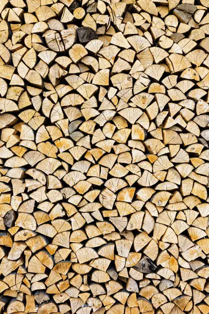 Stacked chopped wood close-up texture. Firewood storage background. Stocks of wooden logs. Chopping wood for a fireplace. Woodpile with firewood with visible wooden texture.