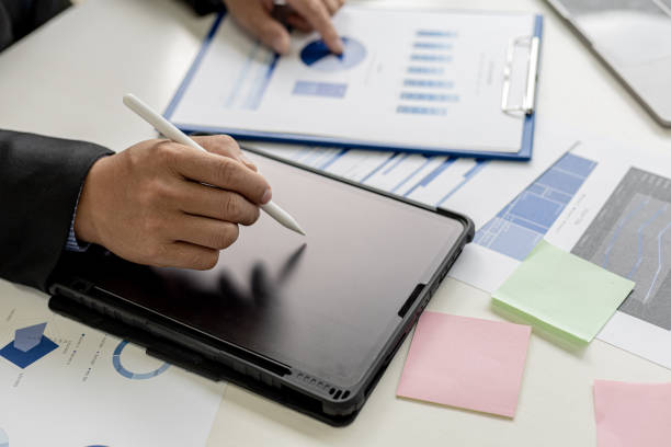 istock Businessman is using tablet to compare information on financial documents, he is checking company financial documents in office, company financial statements. Concept of financial management. 1339674448