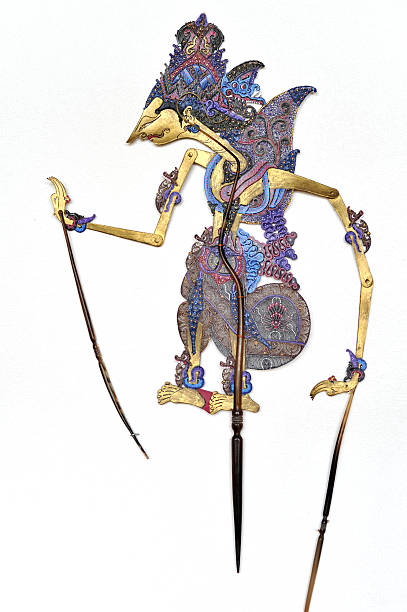 Indonesian traditional Wayang Kulit  puppet hanging on white wall Indonesian flat wayang shadow puppet hanging on a white textured wall.The puppet is made of leather and is carefully chiseled.The handles and control rod are made of buffalo horn. wayang kulit photos stock pictures, royalty-free photos & images