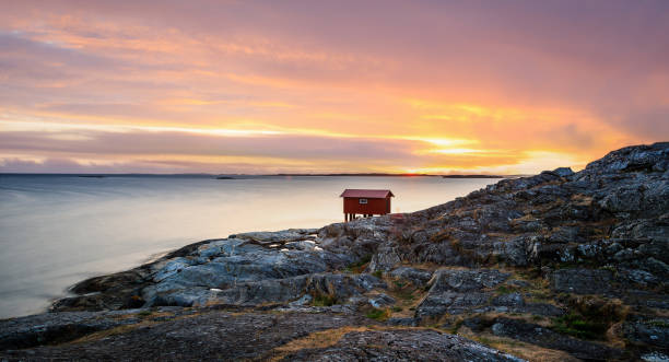 красочный закат красной маленькой рыбацкой хижины на побережье швеции. лонге экспозиция - fishing hut стоковые фото и изображения