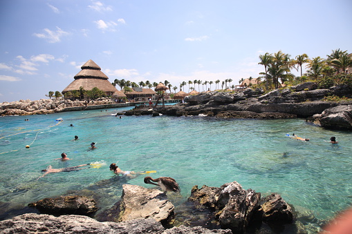 Visitors mingling on Fundadores Park beach at Playa del Carmen on the Caribbean coast of Riviera Maya with performers under the Portal Maya sculpture.