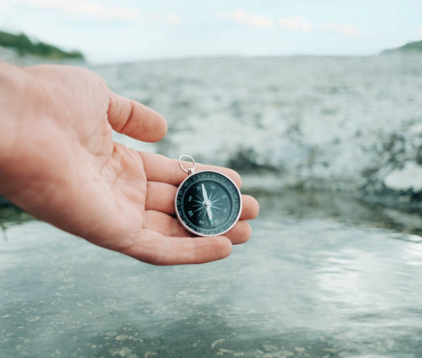 istock Man holds a compass near the river bank. 1339682326