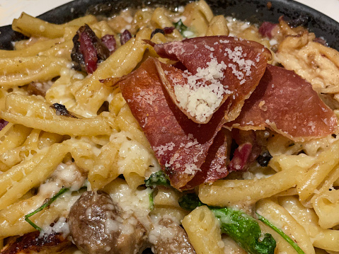 Stock photo showing close-up view of an Italian spaghetti carbonara recipe dish dining out at restaurant with pasta dish of spaghetti, chorizo, pancetta and mushrooms garnished with flat leaf parsley.