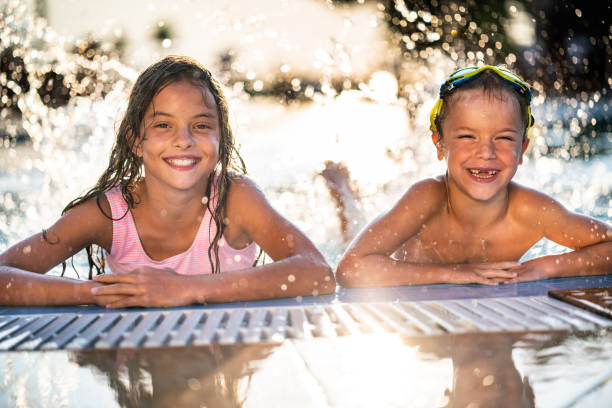 istock Brother and sister having fun in swimming pool 1339684947