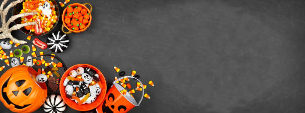 Halloween trick or treat corner border with jack o lantern pails and a variety of candy on a black banner background Halloween trick or treat corner border with jack o lantern pails and a variety of candy. Above view on a black banner background with copy space. indulgence stock pictures, royalty-free photos & images