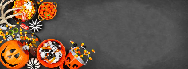 Halloween trick or treat corner border with jack o lantern pails and a variety of candy on a black banner background Halloween trick or treat corner border with jack o lantern pails and a variety of candy. Above view on a black banner background with copy space. halloween candy stock pictures, royalty-free photos & images