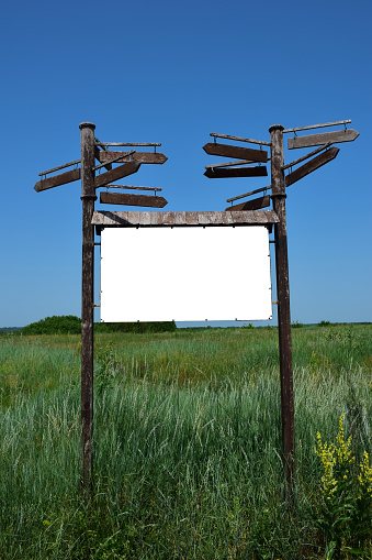 Decorative large signpost of three horizontal boards with blank space for inscriptions on each of them against a background of green grass
