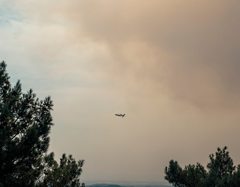 A firefighting airplane flying through smoke and carrying water to Manavgat forest fire in Antalya, Turkey.