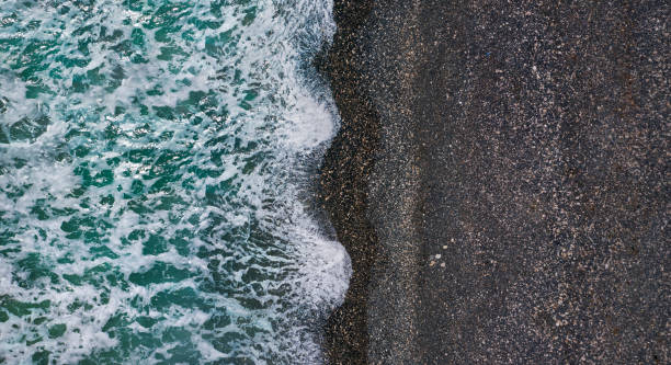 istock Dramatic stormy waves with white sea foam over black sand beach, aerial texture 1339691885