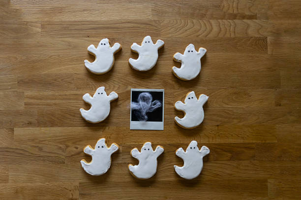 istock Square Halloween table top view with copy space and ghosts sugar cookies around a retro photo from a ghost 1339694069