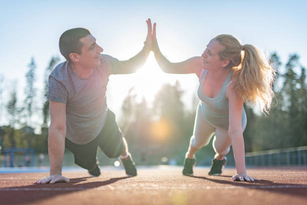 Men and woman doing high five while exercising together stock photo
