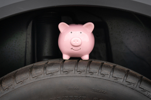 Piggy bank sits on the tire of the car