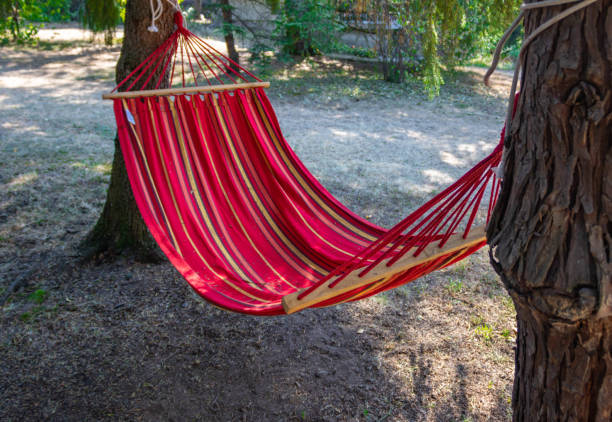 Empty red hammock in the shade between two trees, leisure time