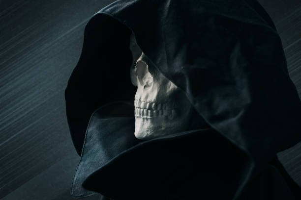 istock Close up view skull in black hood on dark background. 1339699415