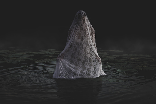 Halloween horror concept. Mysterious ghost like woman in a pond, horror scene.