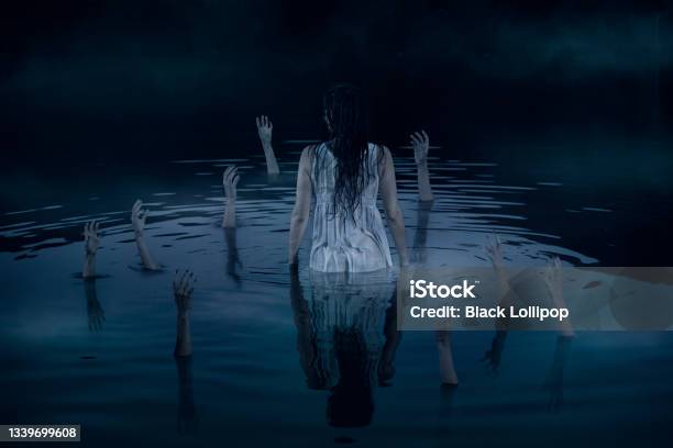A Woman Stands In The Middle Of The Lake Surrounded By Arms Reaching Out Of Deep Dark Water Stock Photo - Download Image Now