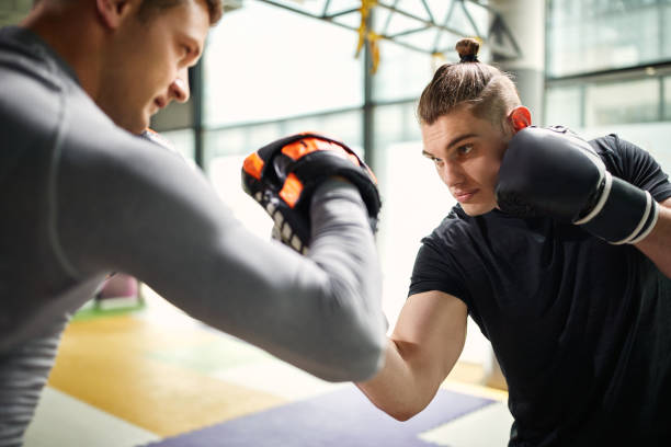 istock Young boxer practicing with his coach at health club. 1339705645
