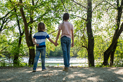 Rear view two kids standing at the riverbank