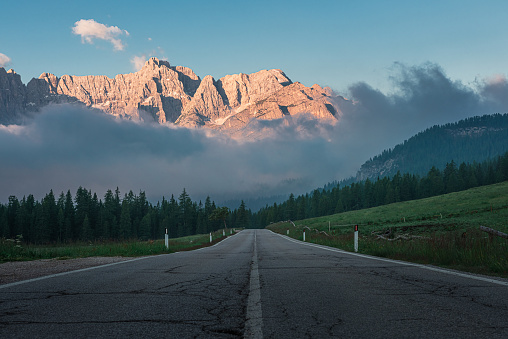 Mountain road in Dolomiti mountains in Italy in foggy morning. Sunrise on the highway in the mountains. Travel concept