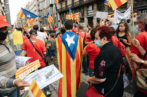 People walking down the street and wearing the colors of the Catalan flag on the national day of Catalonia in Barcelona.