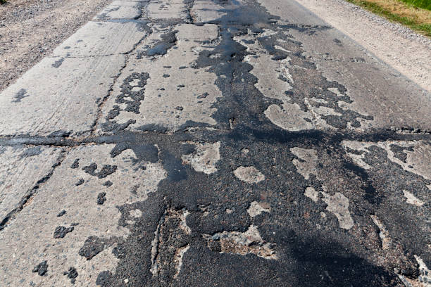 istock a bad asphalt road that has been repaired many times 1339729114