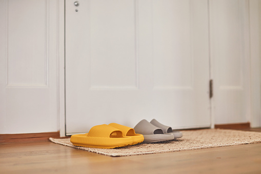Bright yellow and gray slip on sandals on door mat in modern home interior