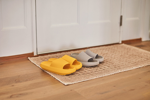 Bright yellow and gray slip on sandals on door mat in modern home interior