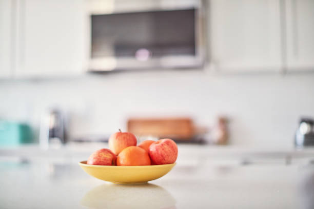 istock Assorted fruit in a yellow bowl on an island in a bright white modern kitchen 1339738291