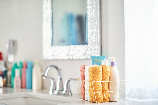 Gold wire basket with washcloths in a bright white modern bathroom