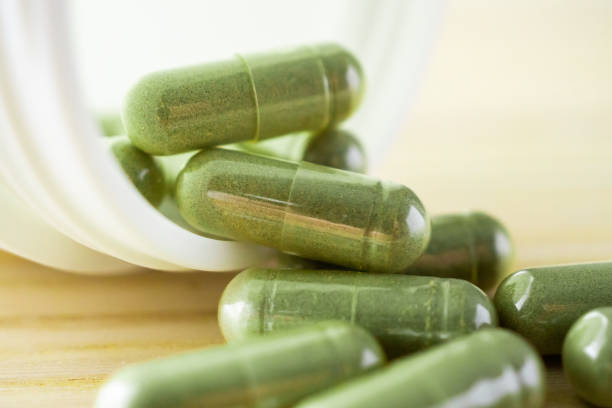 istock Herbal medicine capsules with bottle on wood table 1339739119