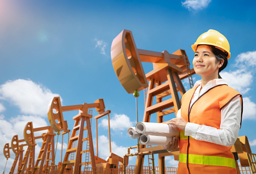 Oil rig engineer or technician wear safety helmet and reflective vest with crude oil pump